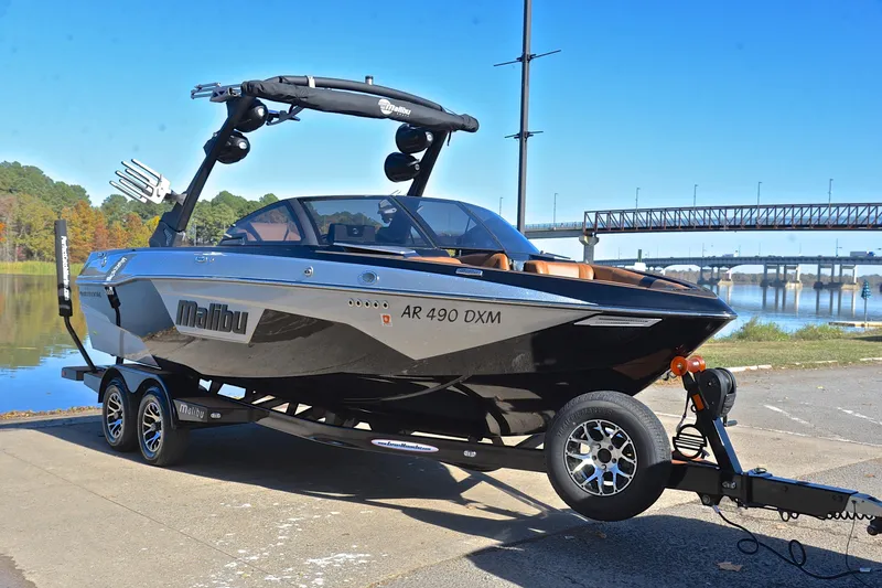 Slide: The Image of 2023 Malibu Wakesetter 23 LSV boat on trailer by riverside with bridge in background. - 16