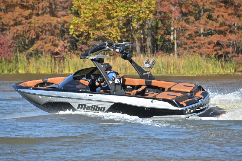 Slide: The Image of 2023 Malibu Wakesetter 23 LSV boat cruising on a lake with autumn foliage backdrop. - 6