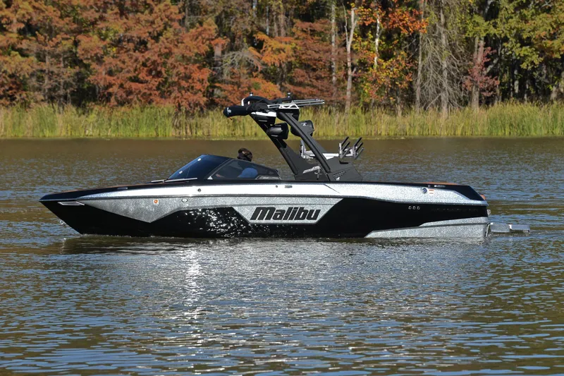 Slide: The Image of 2023 Malibu Wakesetter 23 LSV boat on a calm lake with autumn trees. - 9