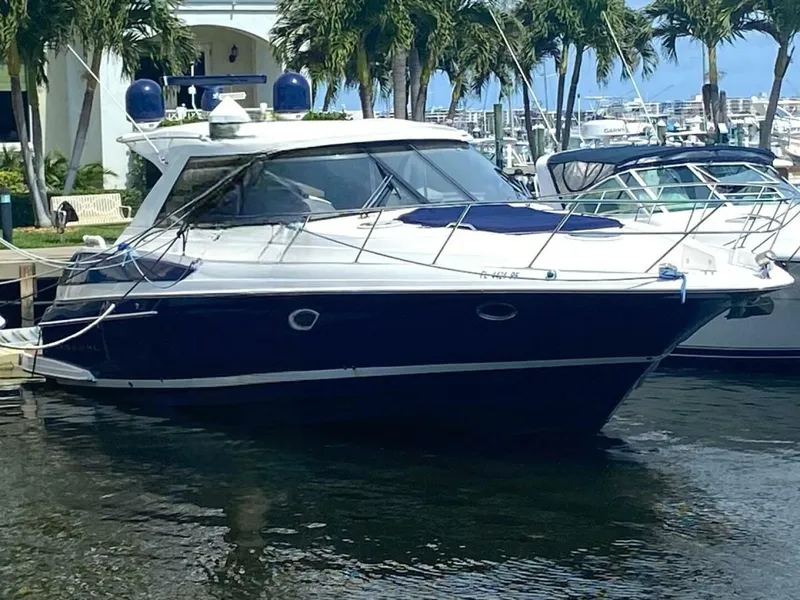 The Image of 2011 Regal 46 Sport Coupe yacht docked in marina, surrounded by palm trees. - 1