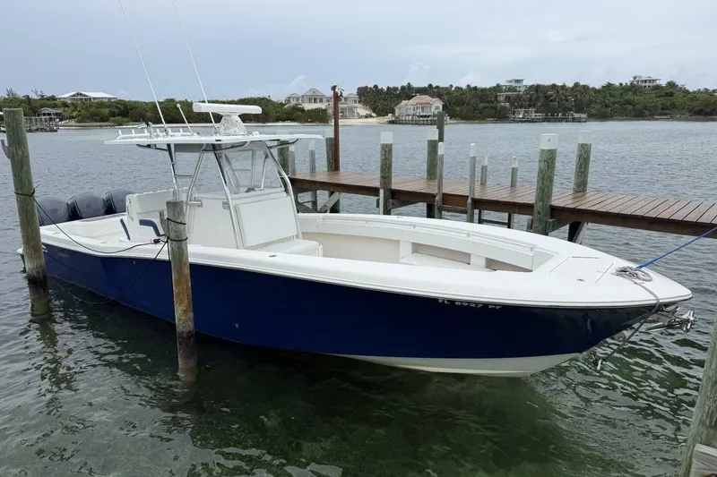 Slide: The Image of 2012 Invincible 36 Open Fisherman boat on trailer, blue hull, parked by a metal building. - 2