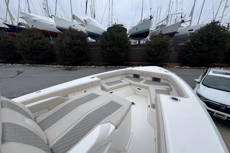 Slide: The Image of 2025 Solace 30 HCS boat interior with cushioned seating, docked near parked cars. - 14