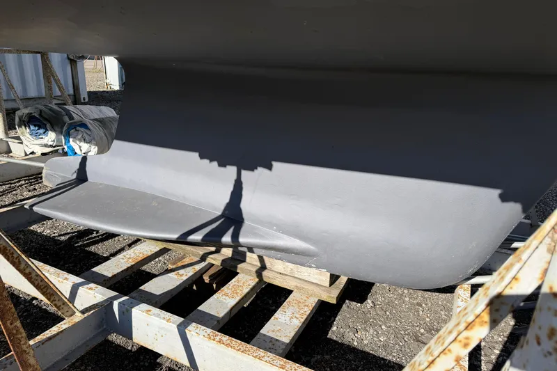 Slide: The Image of Keel of 2003 Hunter 44 Deck Salon sailboat on a stand, with shadows and equipment nearby. - 13