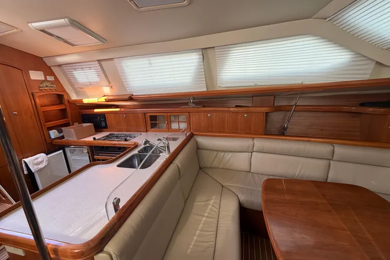 Slide: The Image of 2003 Hunter 44 Deck Salon interior with kitchen, seating, and wooden cabinetry. - 16