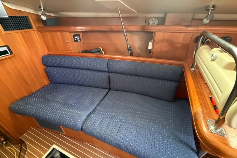 Slide: The Image of Interior of 2003 Hunter 44 Deck Salon with blue cushioned seating and wooden paneling. - 17