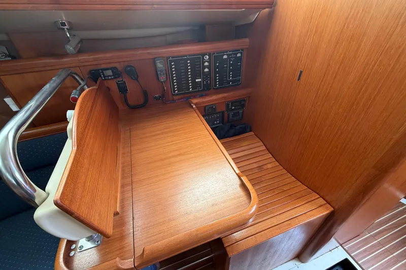 Slide: The Image of 2003 Hunter 44 Deck Salon navigation station with wooden finish and control panels. - 18