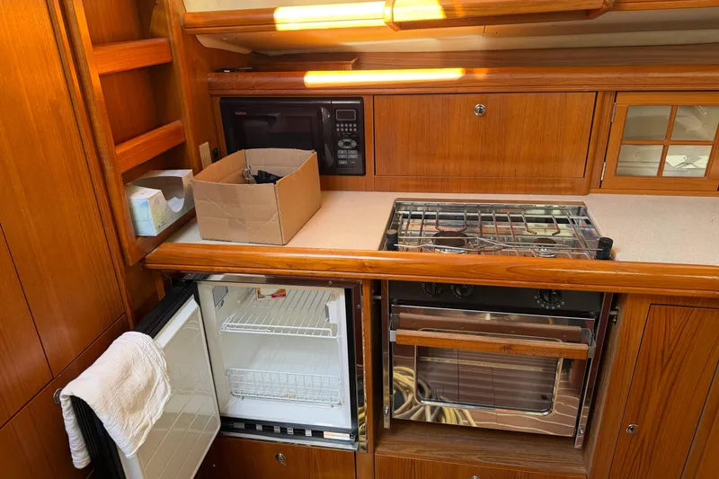 Slide: The Image of 2003 Hunter 44 Deck Salon kitchen with stove, fridge, and microwave. - 26