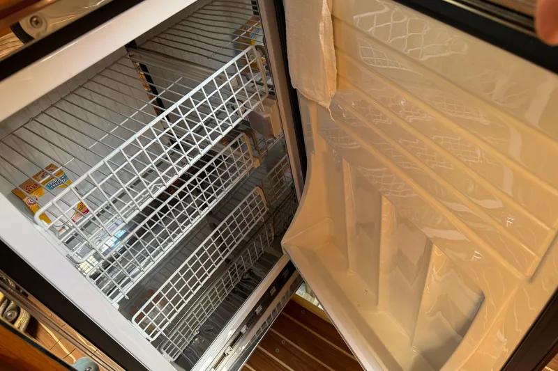 Slide: The Image of Open refrigerator on 2003 Hunter 44 Deck Salon yacht, showing empty wire shelves. - 28