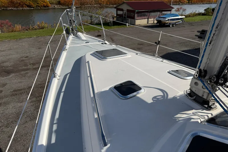 Slide: The Image of 2003 Hunter 44 Deck Salon sailboat deck view near a river and boathouse. - 66