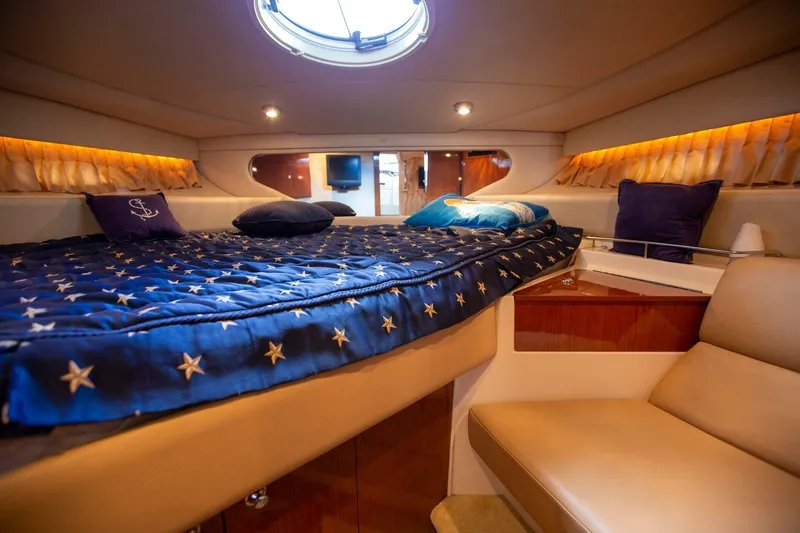 Slide: The Image of Luxurious 2008 Regal 38 yacht cabin with star-patterned bedding and cozy seating. - 10