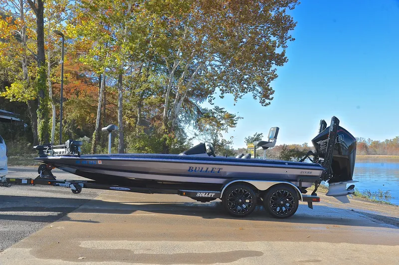 Slide: The Image of 2023 Bullet 21XRS boat on trailer by a lake, surrounded by autumn trees. - 11