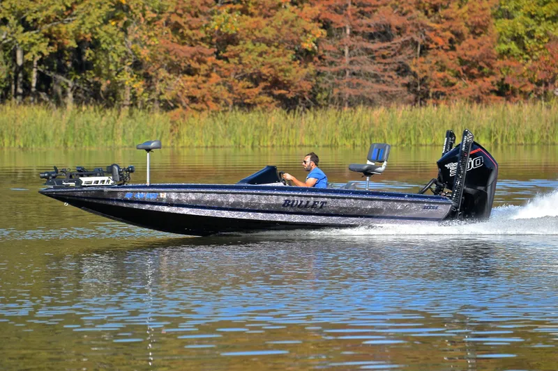 Slide: The Image of 2023 Bullet 21XRS boat speeding on a lake with autumn trees in the background. - 2