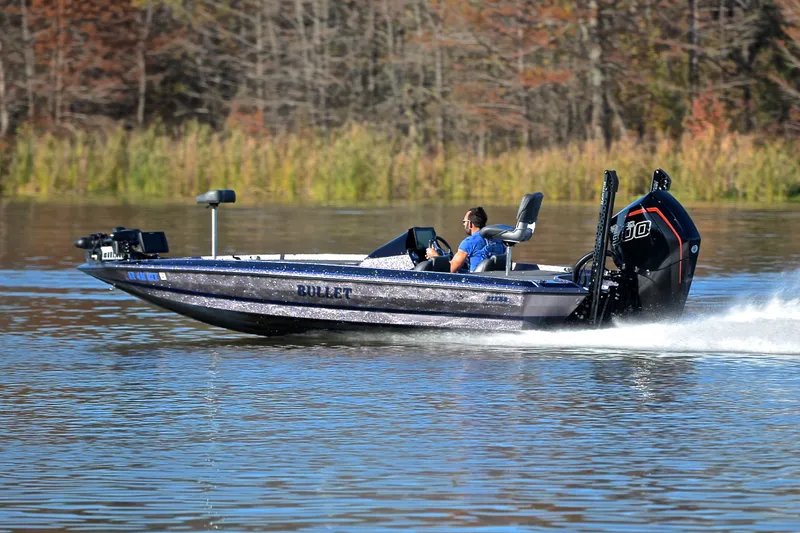 Slide: The Image of 2023 Bullet 21XRS boat speeding on a lake with a driver, surrounded by autumn foliage. - 4