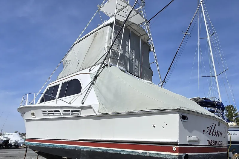 Slide: The Image of 1980 Jersey 40FT Convertible boat on land, covered, with clear blue sky background. - 10