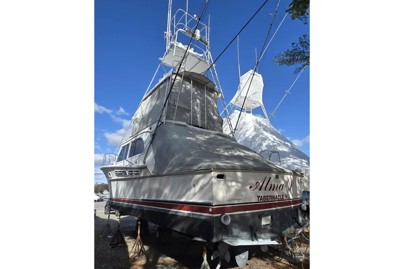 Slide: The Image of 1980 Jersey 40FT Convertible boat on land, covered, with clear blue sky background. - 18