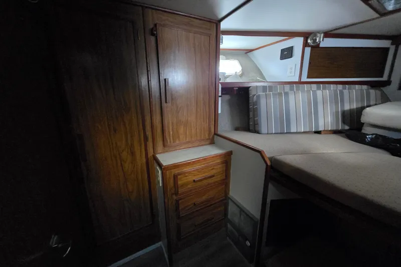 Slide: The Image of Interior of 1980 Jersey 40FT Convertible boat with wooden cabinets and striped cushions. - 21