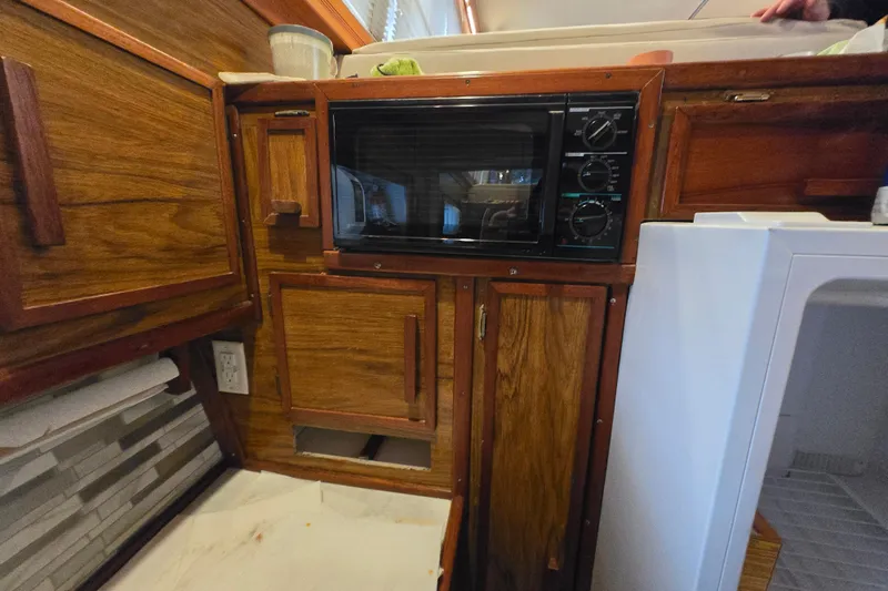 Slide: The Image of 1980 Jersey 40FT Convertible kitchen with wooden cabinets, microwave, and refrigerator. - 23