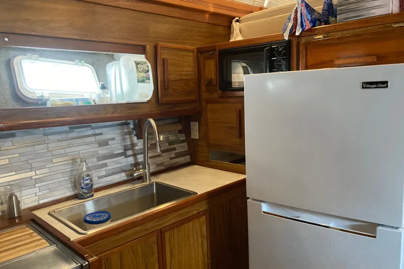 Slide: The Image of 1980 Jersey 40FT Convertible kitchen with wood cabinets, sink, and Magic Chef fridge. - 46