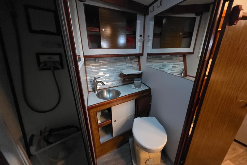 Slide: The Image of 1980 Jersey 40FT Convertible yacht bathroom with sink, toilet, and wooden cabinetry. - 8