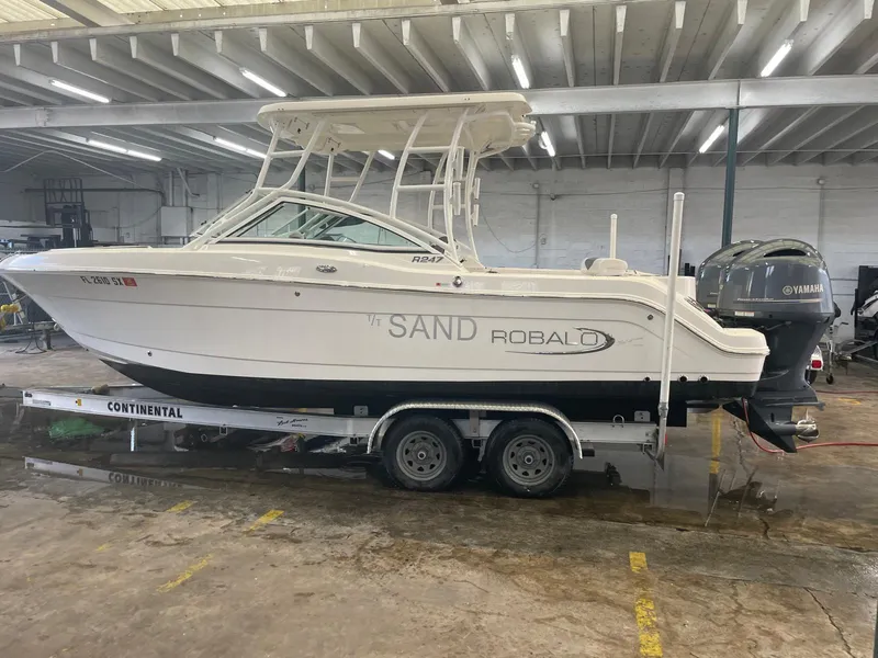 Slide: The Image of 2021 Robalo R247 Dual Console boat on trailer in indoor storage. - 2