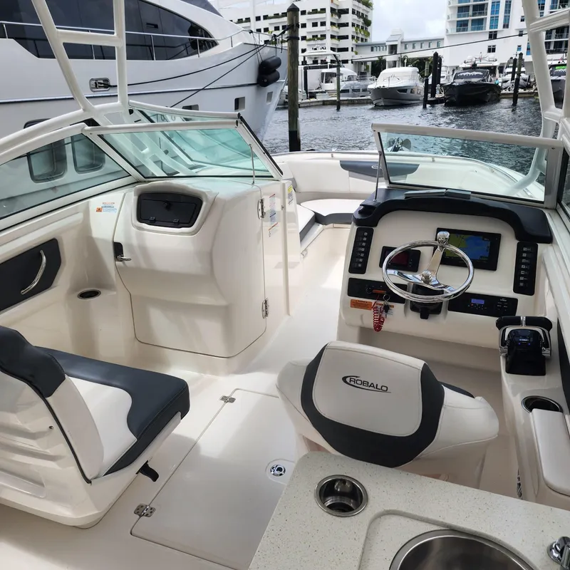 Slide: The Image of 2021 Robalo R247 Dual Console boat interior with helm, seating, and marina view. - 6