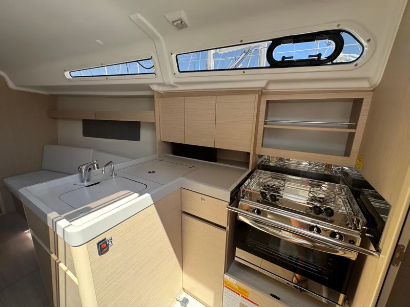 Slide: The Image of 2024 Beneteau Oceanis 34.1 yacht interior kitchen with stove, sink, and storage cabinets. - 8