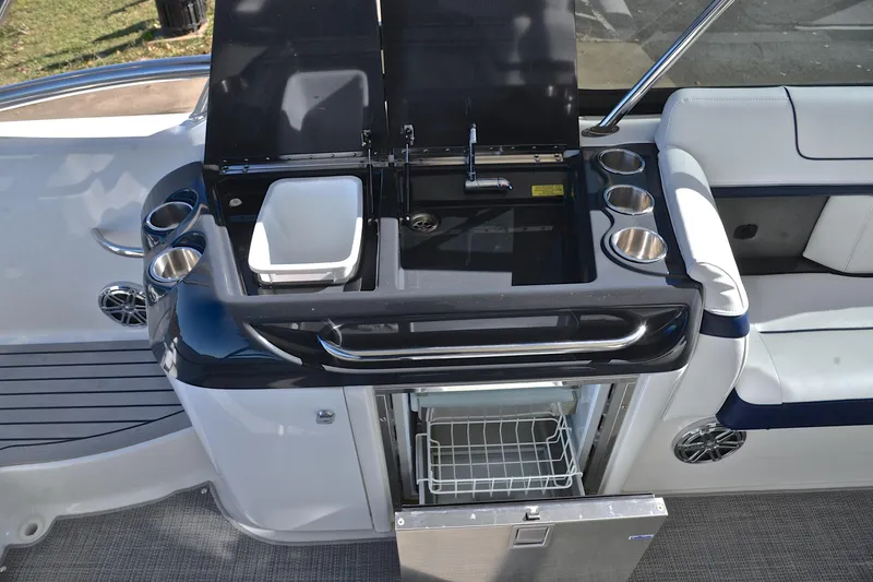 Slide: The Image of 2016 Formula 350 Crossover Bowrider boat kitchen with sink, fridge, and cup holders. - 26
