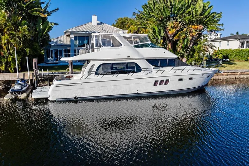 Slide: The Image of 2009 Carver 56 Voyager SE yacht docked by waterfront home with lush greenery. - 10