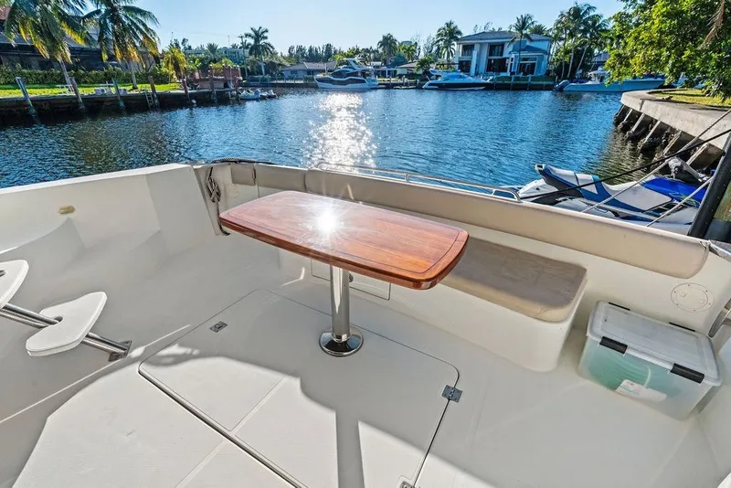 Slide: The Image of 2009 Carver 56 Voyager SE yacht deck with wooden table, overlooking serene waterfront. - 12
