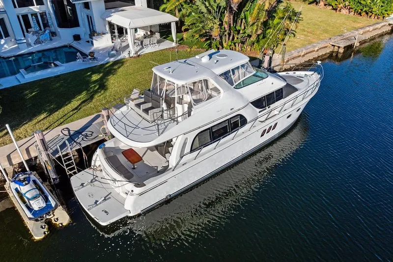 Slide: The Image of 2009 Carver 56 Voyager SE yacht docked by a luxurious waterfront home. - 2