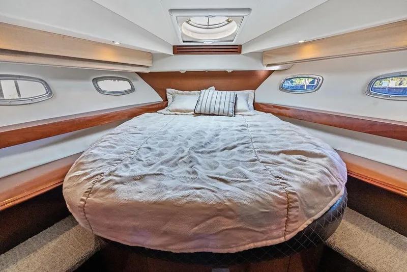 Slide: The Image of Luxurious 2009 Carver 56 Voyager SE yacht bedroom with cozy bedding and porthole windows. - 32