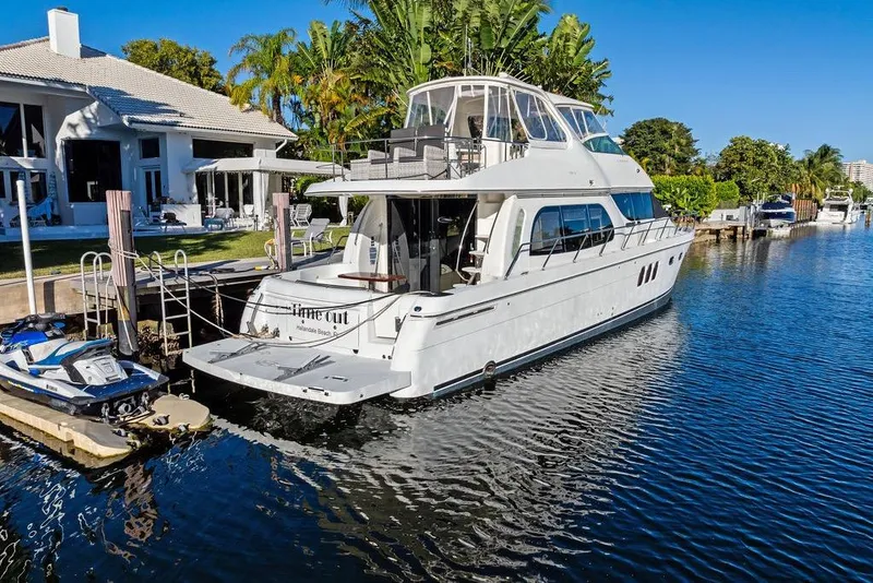 Slide: The Image of 2009 Carver 56 Voyager SE yacht docked by waterfront home, surrounded by lush greenery. - 3
