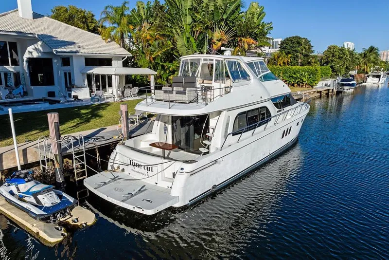 Slide: The Image of 2009 Carver 56 Voyager SE yacht docked by a waterfront home with lush greenery. - 7