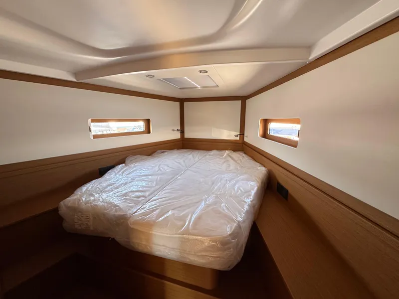 Slide: The Image of 2024 Beneteau First 44 cabin interior with bed, wooden accents, and windows. - 14