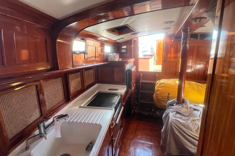 Slide: The Image of Interior of 1966 Moody Salar Motorsailer, featuring wood paneling and compact kitchen area. - 11