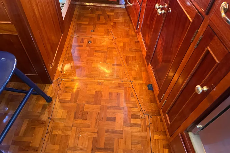 Slide: The Image of Polished wooden interior of a 1966 Moody Cutter, featuring parquet flooring and cabinetry. - 5
