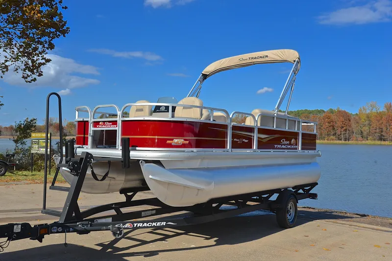 Slide: The Image of 2023 Sun Tracker Bass Buggy 18 DLX pontoon boat on trailer by a lake. - 10