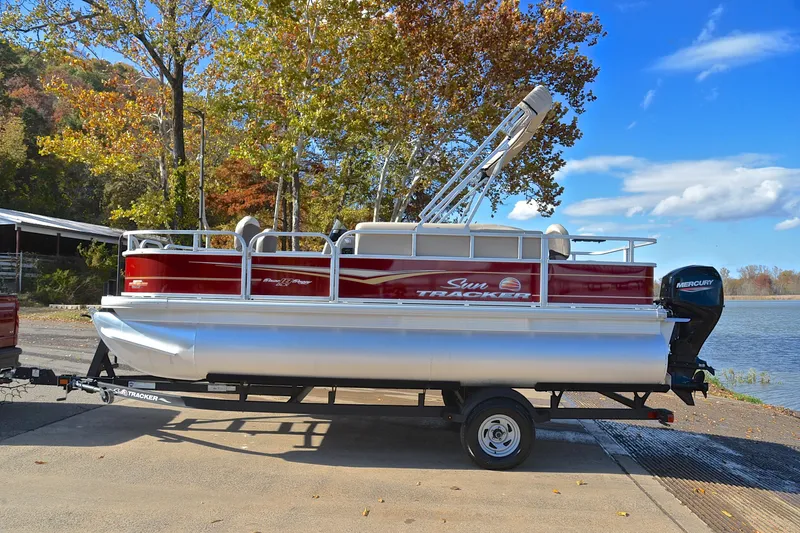 Slide: The Image of 2023 Sun Tracker Bass Buggy 18 DLX pontoon boat on trailer by a lake. - 11