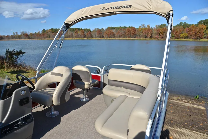Slide: The Image of 2023 Sun Tracker Bass Buggy 18 DLX pontoon boat on a scenic lake. - 22
