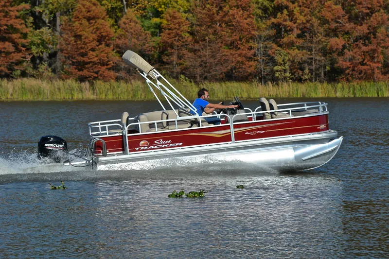 Slide: The Image of 2023 Sun Tracker Bass Buggy 18 DLX pontoon boat cruising on a scenic lake. - 3