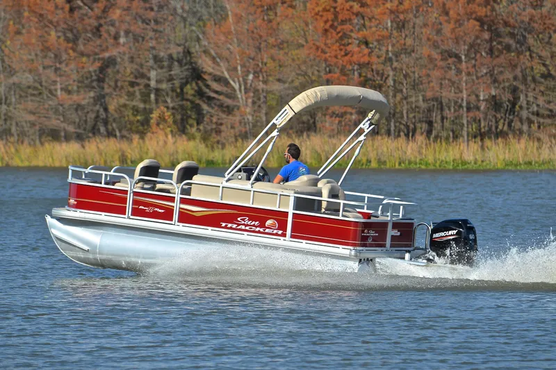 Slide: The Image of 2023 Sun Tracker Bass Buggy 18 DLX pontoon boat cruising on a lake. - 4