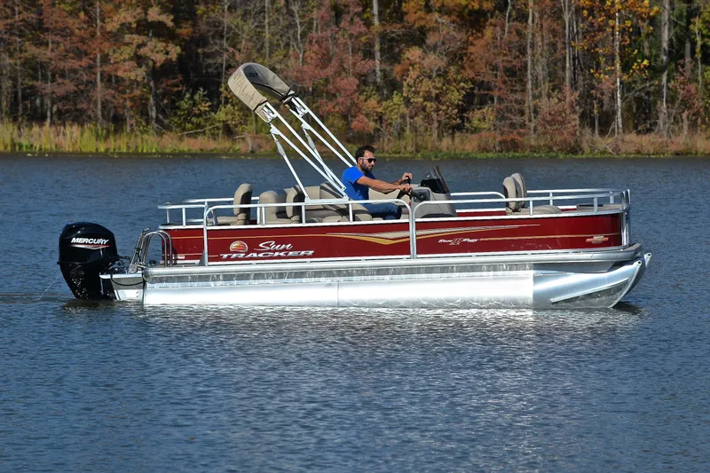 Slide: The Image of 2023 Sun Tracker Bass Buggy 18 DLX pontoon boat cruising on a lake. - 6