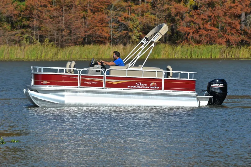 Slide: The Image of 2023 Sun Tracker Bass Buggy 18 DLX pontoon boat cruising on a lake. - 8