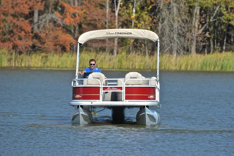 Slide: The Image of 2023 Sun Tracker Bass Buggy 18 DLX pontoon boat on a serene lake. - 9