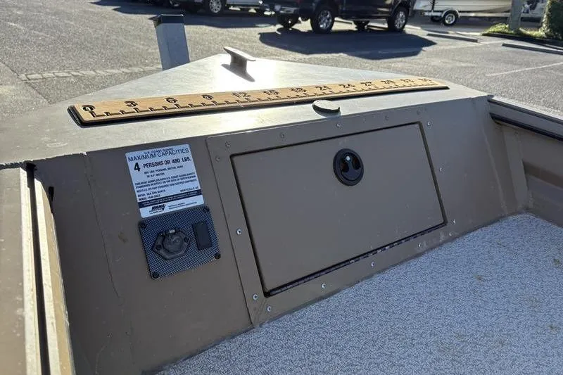 Slide: The Image of 2025 SeaArk DXS 1548 DKLD boat interior with storage compartment and capacity label. - 14