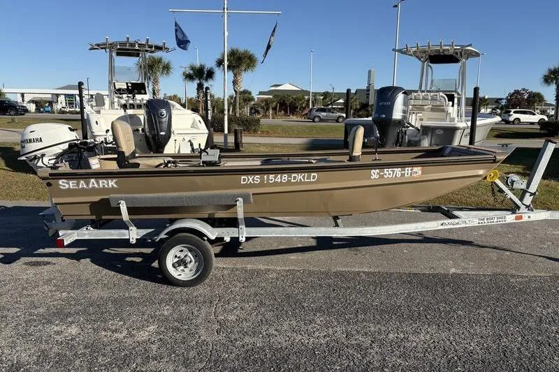 Slide: The Image of 2025 SeaArk DXS 1548 DKLD boat on trailer, parked outdoors. - 4