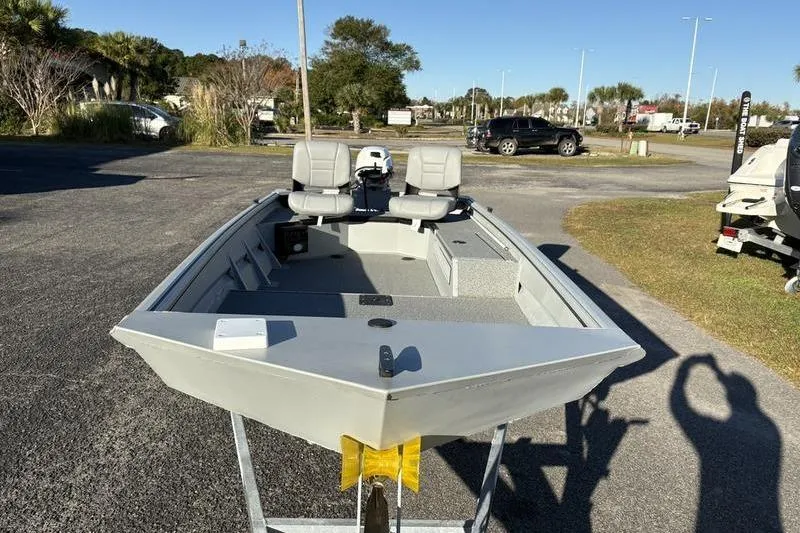 Slide: The Image of 2025 SeaArk DXS 1548 DKLD boat on trailer, parked outdoors in sunny setting. - 4