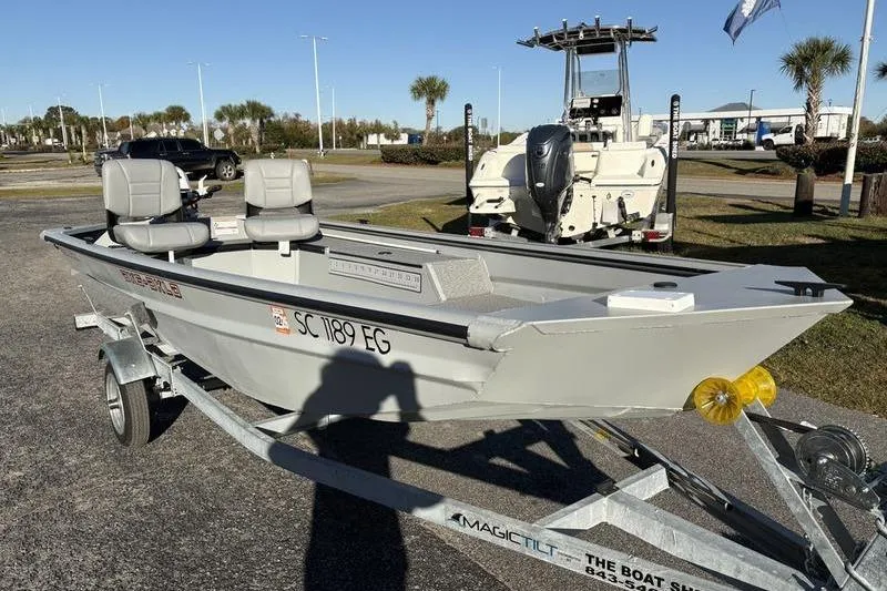 Slide: The Image of 2025 SeaArk DXS 1548 DKLD boat on trailer, parked outdoors in sunny setting. - 8