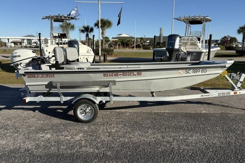 Slide: The Image of 2025 SeaArk DXS 1548 DKLD boat on trailer, parked outdoors. - 9