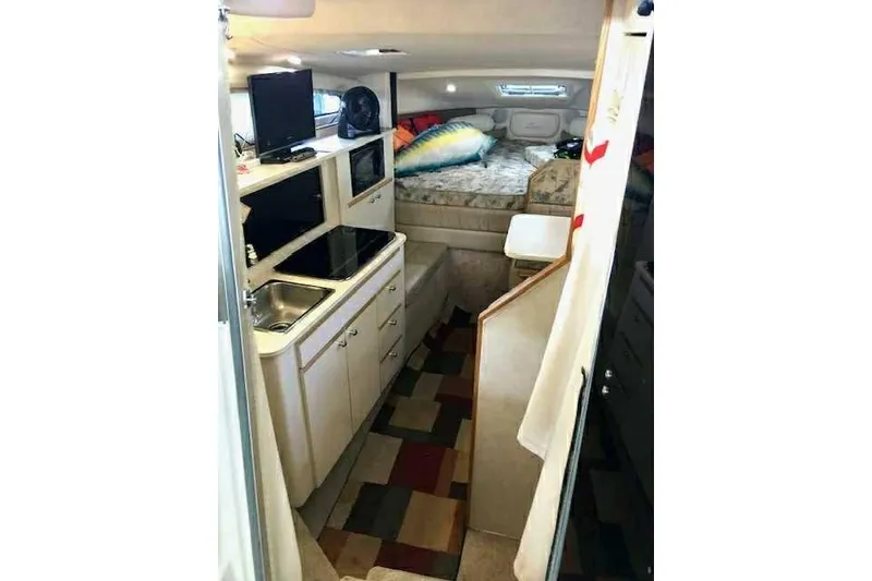 Slide: The Image of 1999 Bayliner 2855 Ciera interior with kitchenette, bed, and colorful rug. - 18